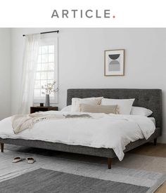 a bed with white sheets and pillows in a bedroom next to a rug on the floor