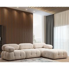 a large white sectional couch in front of a wooden wall with vertical blinds and drapes