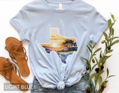 Looking for a shirt that captures the beauty of Texas bluebonnets? Look no further than this stunning watercolor design, featuring the iconic flowers in a dreamy, ethereal style. But that's not all: the bluebonnets are set against the outline of the Lone Star State itself, making this shirt the perfect way to show your love for the great state of Texas. Whether you're a native Texan or just a fan of the state's natural beauty, this shirt is sure to become a favorite in your wardrobe. Made with h Blue Watercolor Print Tops For Spring, Blue Watercolor Print Top For Spring, Blue Short Sleeve Tops With Watercolor Print, Blue Short Sleeve Top With Watercolor Print, Blue Custom Print T-shirt For Spring, Texas Themed Gifts, Texas Outline, Ethereal Style, Texas Shirt