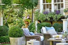 an outdoor patio with chairs, tables and potted plants on the side of it