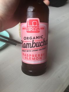 a person holding up a bottle of organic kombucha raspberry lemon