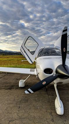 a small white airplane sitting on top of an airport tarmac with the door open