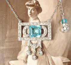 "Offering a stunning antique Art Deco/Edwardian 1920s to 1930s era open back aquamarine blue cut crystal and clear paste rhinestone pendant necklace.  The perfect \"Something Old\" and \"Something Blue\" for the Bride! Photos don't begin to do this one justice.  The 1 3/4 inch high and 1 1/2 inches (3.7 cm) wide pot metal ornate open work pendant features a phenomenal open backed square cushion cut aqua blue sparkly cut glass crystal rhinestone.   The setting is adorned with milgrain edges and s Heirloom Blue Necklaces For Weddings, Victorian Turquoise Necklace For Wedding, Blue Art Deco Jewelry For Wedding, Vintage Wedding Gemstone Necklaces, Vintage Blue Jewelry For Wedding, Vintage Blue Wedding Jewelry, Vintage Light Blue Jewelry For Wedding, Vintage Light Blue Wedding Jewelry, Light Blue Vintage Wedding Jewelry