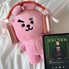 a pink teddy bear with headphones next to an mp3 player