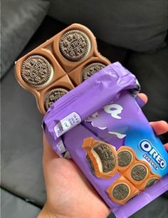 a person holding up a chocolate bar with oreo cookies on the front and one in the back