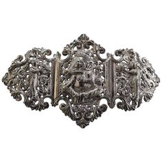 This is a highly ornate and decorative old Anglo-Indian silver belt buckle with red and black ribbon belts. It dates to the early 20th century and is made up of three separate sections - two panels are joined by a hinge and the third separates to act as the buckle clasp. Each panel has a little Hindu figure (Krishna in the middle). Box has 4079 stamped on side and measures 5 1/4 inches X 3 1/4 inches X 1 1/14 inches. The belts or ribbons measure 25 inches X 2.5 inches. Antique Engraved Belt Buckles For Formal Wear, Antique Silver Belt Buckles Collectible, Antique Silver Belt Buckles For Collectibles, Antique Silver Collectible Belt Buckles, Dragon Bracelet, Silver Belt Buckle, Masonic Ring, Silver Belt, Ribbon Belt