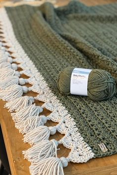 a ball of yarn sitting on top of a table next to a green and white blanket