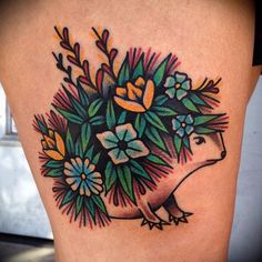 a woman's thigh with flowers and an hedgehog tattoo on the side of her leg