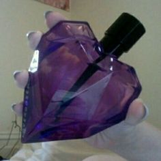 a person holding a purple perfume bottle in their hand