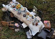 an old fashioned picnic table set up in the grass with tea cups and plates on it