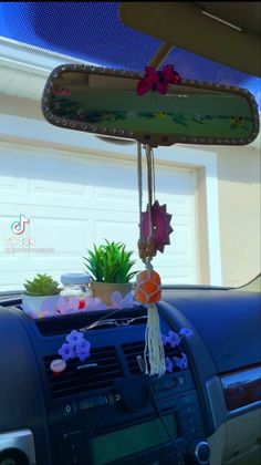 an air freshener hanging from the dashboard of a car with flowers and plants in it