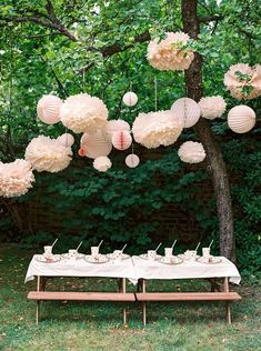 a table topped with paper lanterns and cupcakes on top of a wooden table