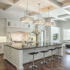 a large white kitchen with an island and bar stools in the middle of it