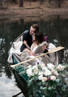 a man and woman are in a boat with flowers on the water, holding onto each other