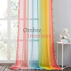 a rainbow colored curtain with pom - poms hanging from it's side