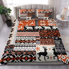 an orange and black quilted comforter on a bed in a room with white walls