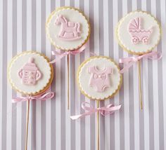 three decorated cookies with pink icing on sticks