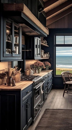 a kitchen with black cabinets and an open door leading to the outside area that overlooks the ocean