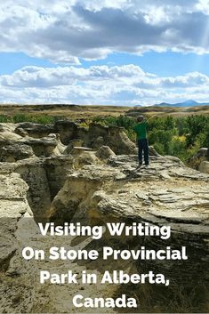 a man standing on top of a rock formation with the words visiting writing on stone provincial park in alberta, canada