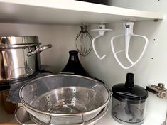 a kitchen shelf with pots and mixers hanging on the wall next to each other