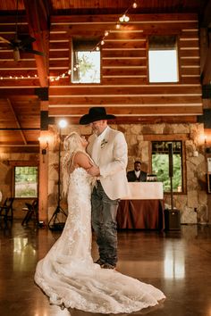 a bride and groom dance together in the reception hall at their rustic barn wedding venue