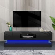 an entertainment center with a large television on it's stand and blue lighting underneath