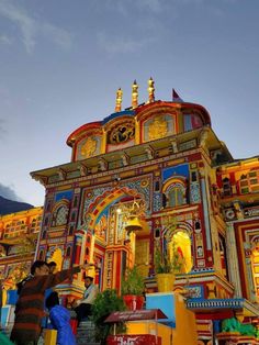 people are standing in front of a brightly colored building that has gold and blue decorations on it