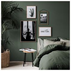 a bedroom with green walls and pictures hanging on the wall above the bed, along with a small side table