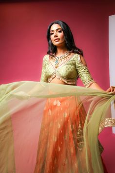 Tangy Pistachio Lehenga - Brocade Indian Wedding Lengha choli with Banarasi and Netted Dupatta Stay on-trend with B Anu Designs' Green Embroidered Lehenga. Made with premium quality fabric, this lehenga set features intricate thread embroidery, creating a beautiful contrast against the orange fabric. Perfect for a wedding or a formal occasion, this lehenga set will make you feel like a true princess. This lehenga set is perfect for a daytime wedding or a formal event, exuding sophistication and Green Semi-stitched Pre-draped Saree With Meenakari, Green Tissue Silk Choli For Festive Occasions, Festive Green Tissue Silk Choli, Green Anarkali Choli In Tissue Silk, Pista Green Organza Choli With Cutdana, Pista Green Organza Choli With Sheer Dupatta, Green Designer Choli With Traditional Drape, Green Tissue Silk Lehenga For Reception, Designer Green Choli With Traditional Drape