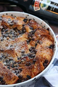 a blueberry cobbler in a white dish next to a bottle of wine