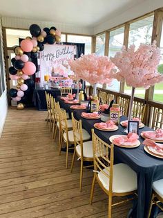 a table set up for a birthday party with pink and black balloons on the wall