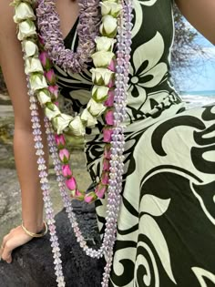 a woman in a dress is holding flowers and beads on her neck with both hands