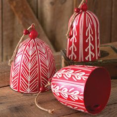 two red and white ornaments sitting on top of a wooden table next to each other