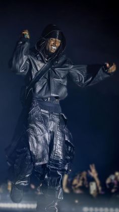 a man in black jacket and leather pants on stage