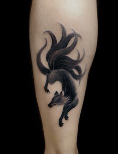 a woman's leg with a black and grey wolf tattoo on the side of her legs