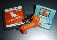 a dog keychain is shown next to a nintendo ds gameboy and an orange rubber toy