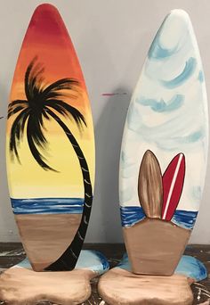 two surfboards are sitting on top of each other in front of the ocean and palm tree