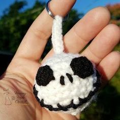 a hand holding a small crocheted panda bear ornament in it's palm