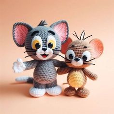 two crocheted mice standing next to each other on a pink surface with one holding the tail of another