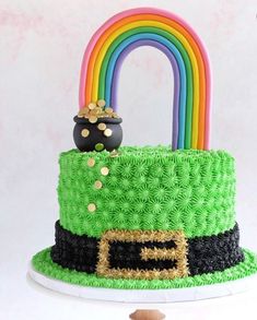 there is a green cake with a rainbow in the middle and a pot on top