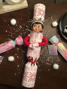 an elf is sitting on top of some toilet paper rolls and other items that are scattered around the table