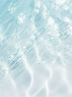 water ripples over the surface of a blue pool with white sand and pebbles in it