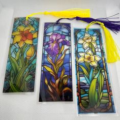 three stained glass bookmarks with yellow tassels and purple flowers on the sides