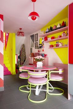 a kitchen with pink and yellow accents, white appliances and shelves on either side of the dining room table