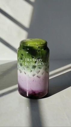 a glass jar sitting on top of a white table next to a shadow from the wall