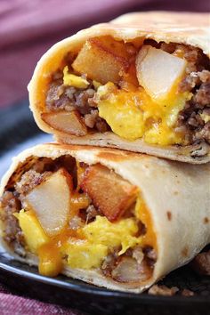 two breakfast burritos sitting on top of a black plate