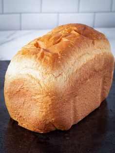 a loaf of bread sitting on top of a black counter next to a white tile wall