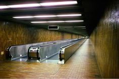 an empty subway station with two escalators on the wall and lights above them