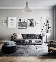 a living room with grey couches and pictures on the wall above them in black and white