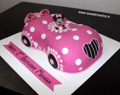 a pink birthday cake with minnie mouse driving a car